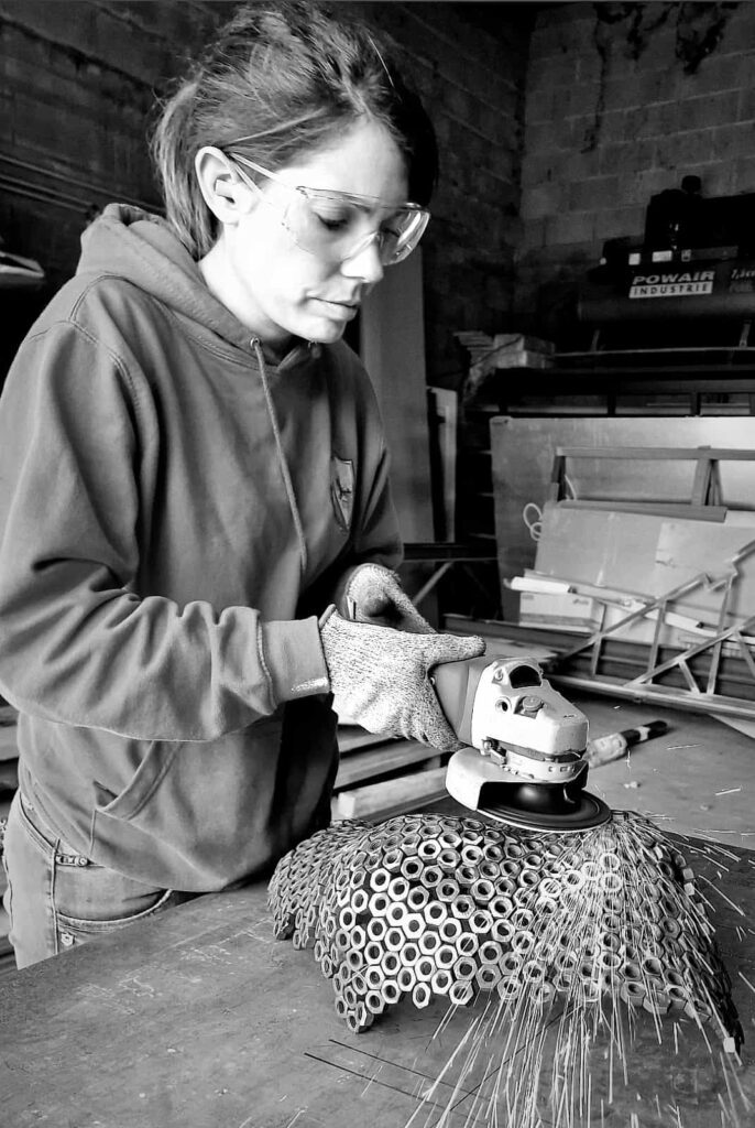 Cindy à l'atelier, soudant une sculpture sur métal