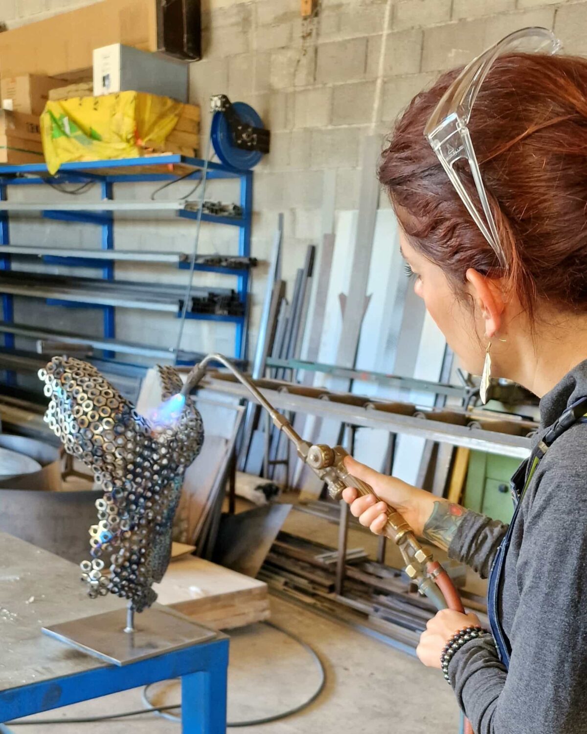 Cindy, chalumeau en main, façonnant une sculpture d'écrous dans l'atelier